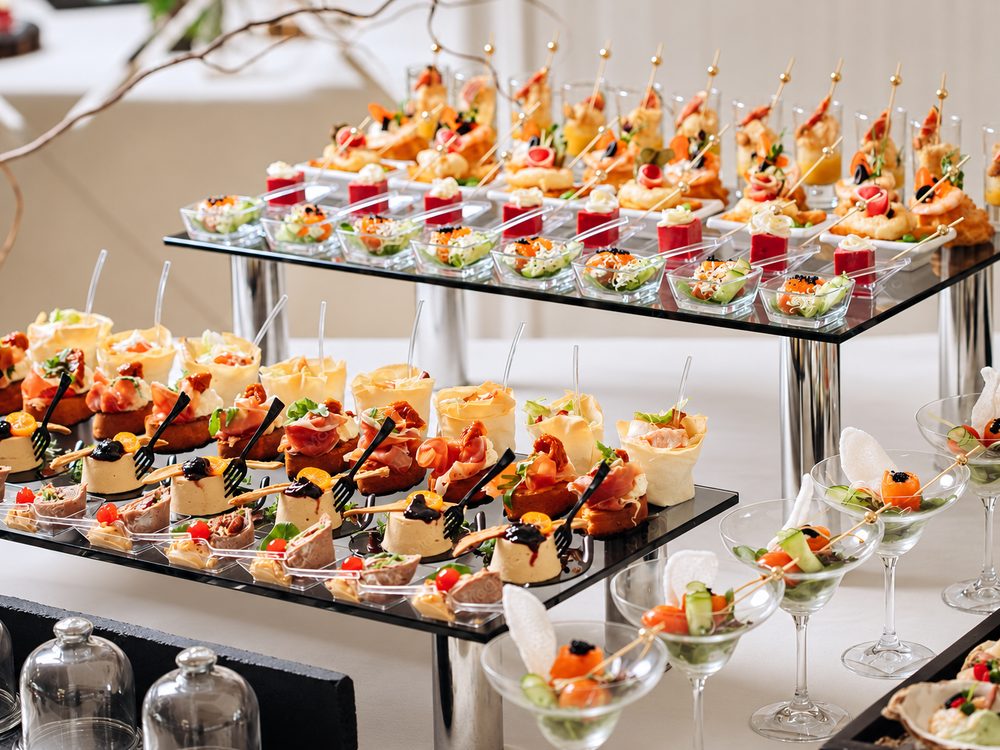 Mesa de catering con bocaditos, copas y brochetas servidos para un evento