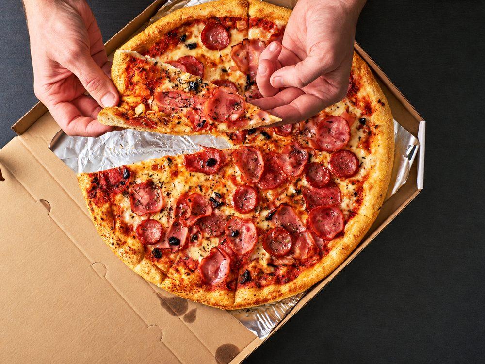 Pizza recién cortada servida en caja de cartón para delivery
